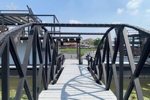 A metal bridge with a walkway leading to a structure with a star-shaped design. - Ban Suan Bang Toei Villa (Sam Phran)