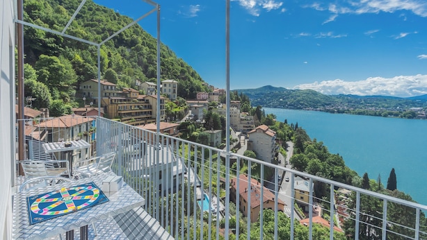 Un balcón con vista a un lago, edificios y un paisaje montañoso.