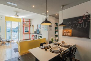 A modern dining area with a table set for four, a chalkboard with writing, and a view through a glass door.