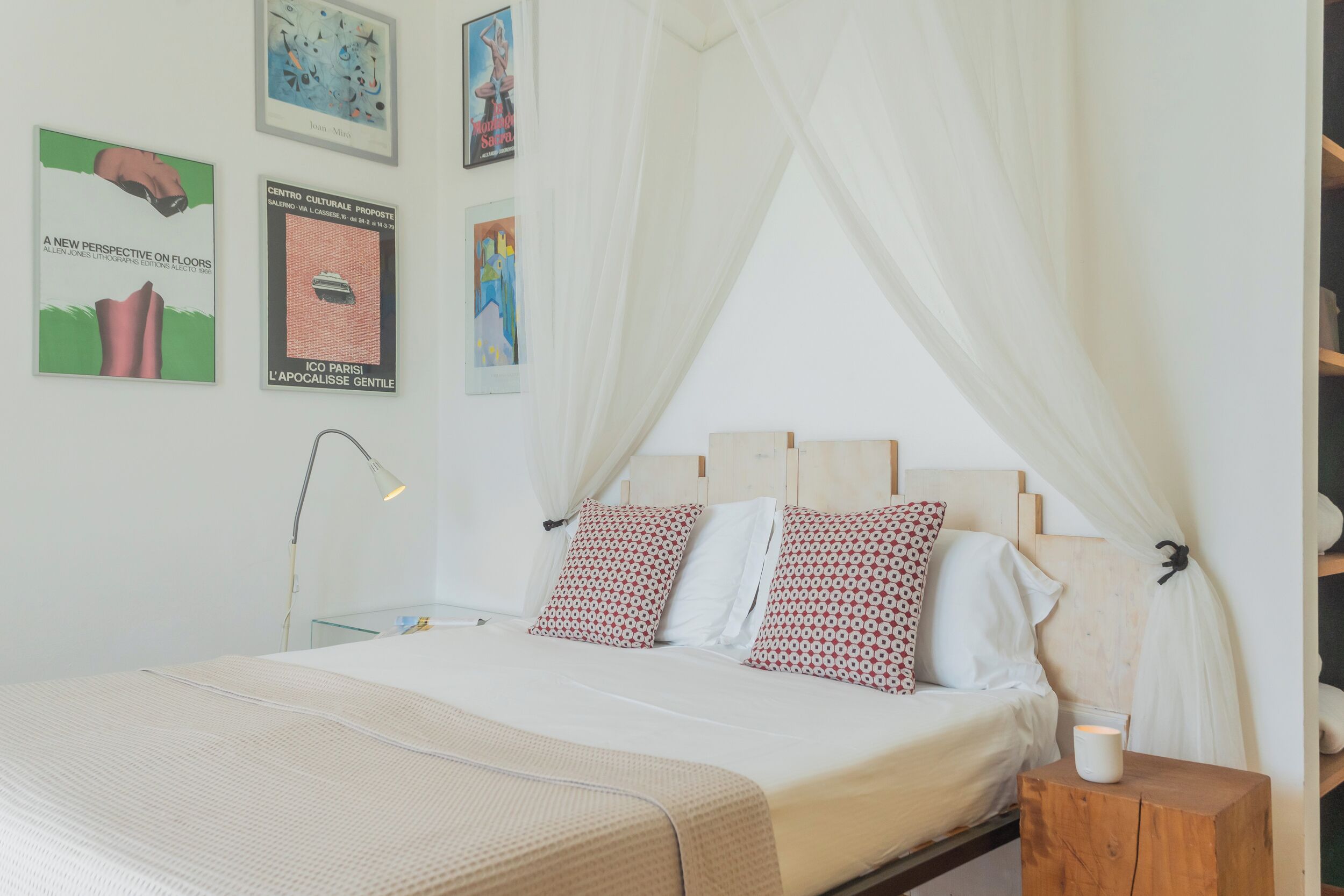 Una cama bien hecha con dosel, una lámpara de noche y una mesita de noche de madera.