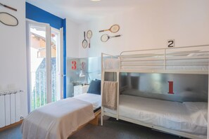 A dormitory room with bunk beds, a window, and a door leading to an outdoor area.
