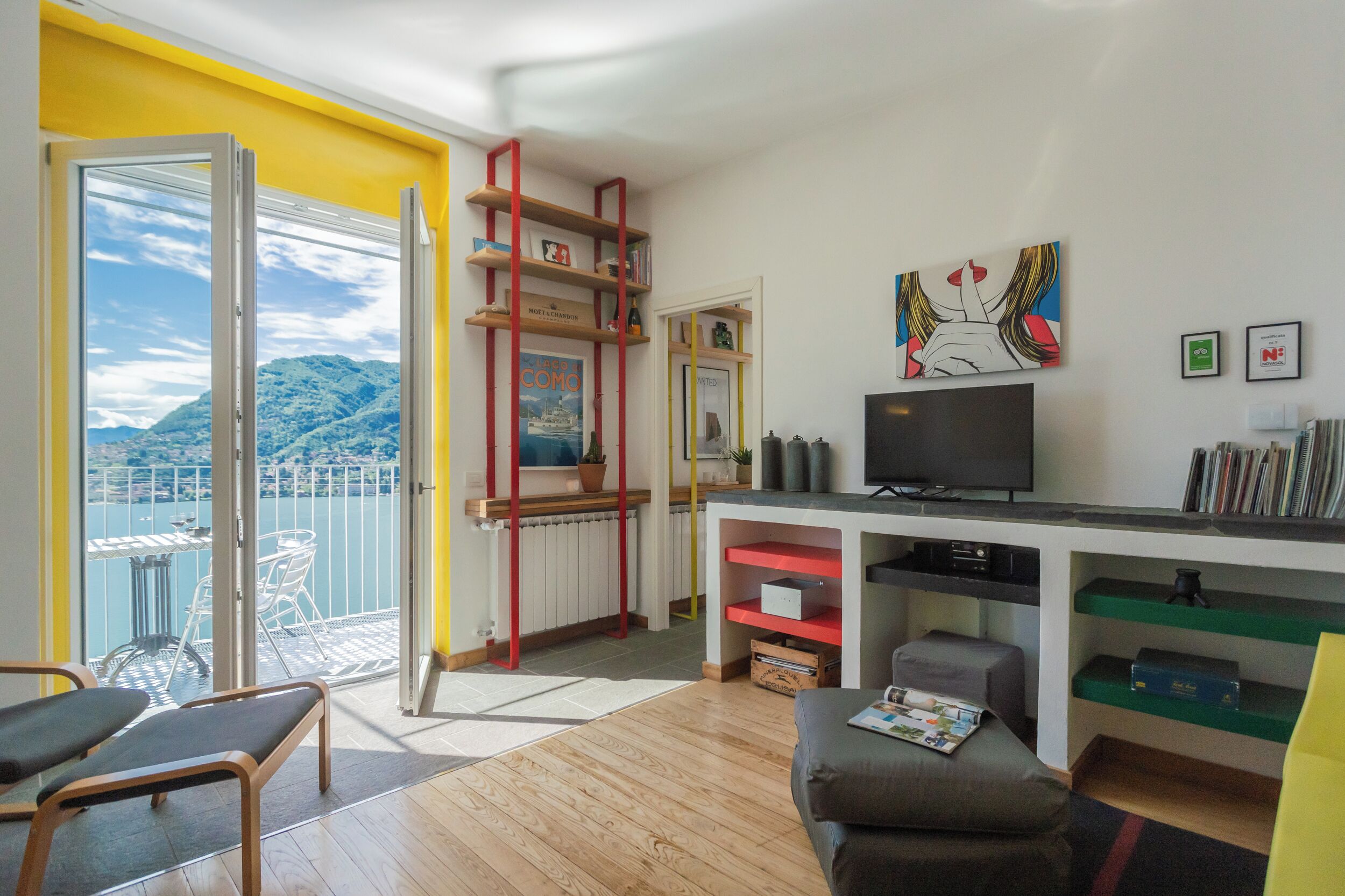 A modern living room with a balcony, a TV, and a bookshelf.