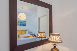 Un dormitorio con cama, mesita de noche, lámpara y un cuadro en la pared.