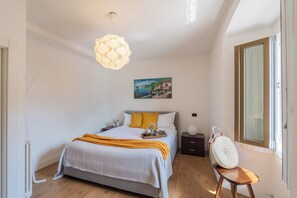 Een slaapkamer met een bed, nachtkastje, lamp en uitzicht op het landschap.