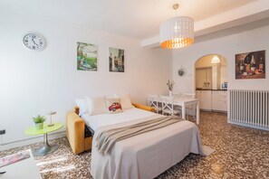 Une chambre à coucher avec un lit, une table de chevet, une lampe et une vue sur la cuisine.