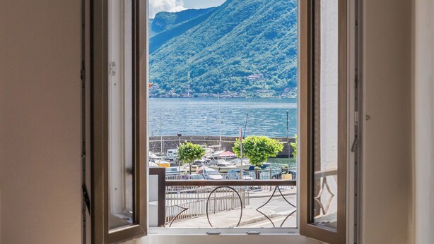 Un balcon offrant une vue sur une marina et un paysage montagneux.