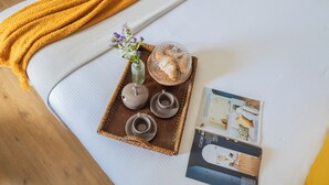Un plateau bien rangé, sur lequel on trouve une théière et des tasses en céramique, un saladier en verre et un vase avec des fleurs, le tout posé sur un canapé blanc.