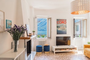 Una sala de estar con chimenea, televisor y vista al mar.