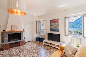 Un salón con chimenea, televisión y vistas a la montaña y al mar.