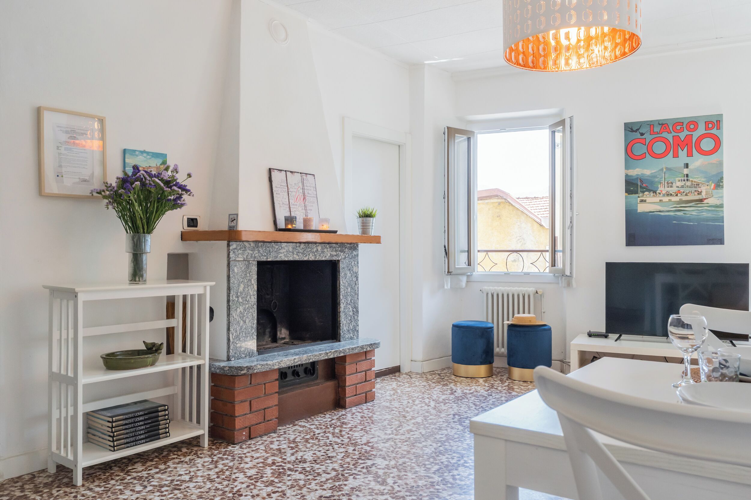 A living room with a fireplace, a dining table, a TV, and a window with a view.