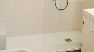 Un cerramiento de ducha con un cabezal de ducha de mano y un grifo empotrado en la pared.