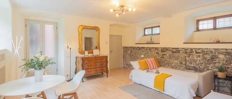 Una habitación luminosa con cama, cómoda, mesa y sillas.
