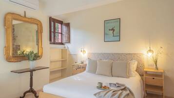 A neatly arranged bedroom with a large bed, bedside tables, a mirror, and a framed picture on the wall.