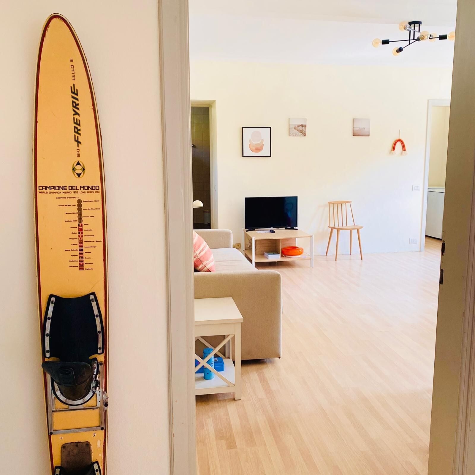 Une chambre avec un lit, une télévision, une chaise et une planche de surf appuyée contre le mur.