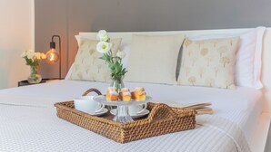 A neatly made bed with a tray of pastries and a vase of flowers. - Harmony on the Lake by Rent all Como (Argegno)