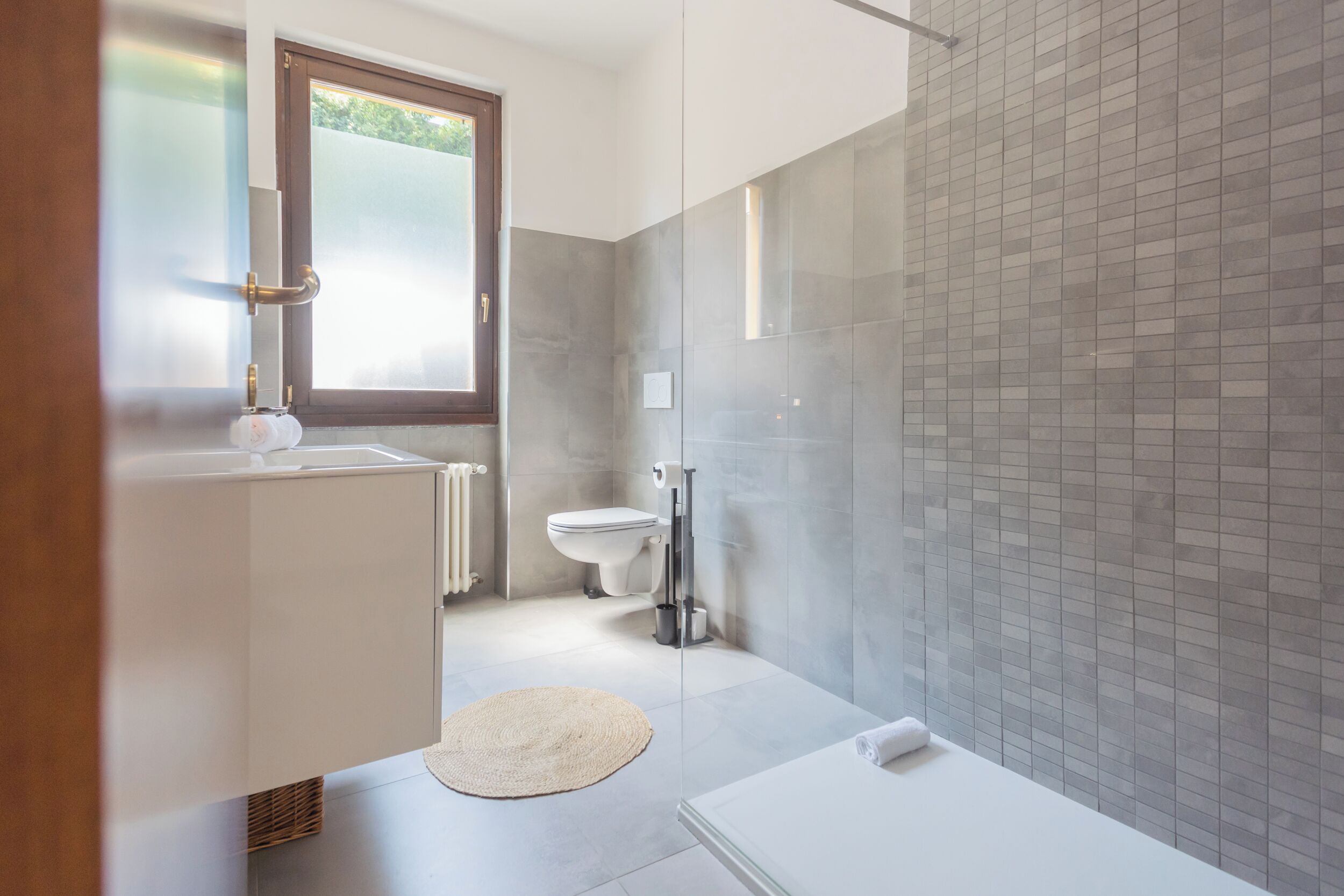 A modern bathroom with a glass shower enclosure, a white bathtub, and a toilet.
