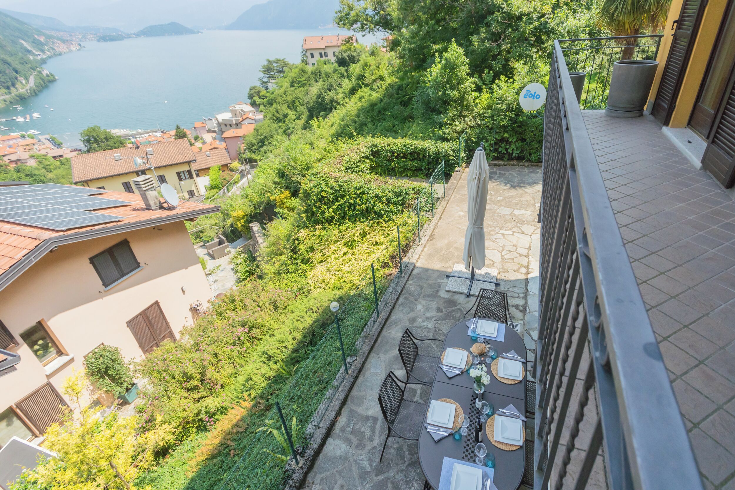 Un balcon avec une table dressée pour le dîner, offrant une vue panoramique sur un lac et les bâtiments environnants.