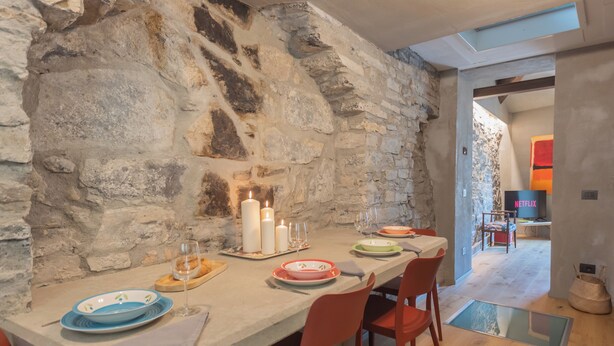 A dining area with a stone wall, a table set with plates, glasses, and candles. - Urio's Castle Suites by Rent all Como (Carate Urio)