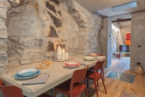 A dining area with a stone wall, a table set with plates, glasses, and candles. - Urio's Castle Suites by Rent all Como (Carate Urio)