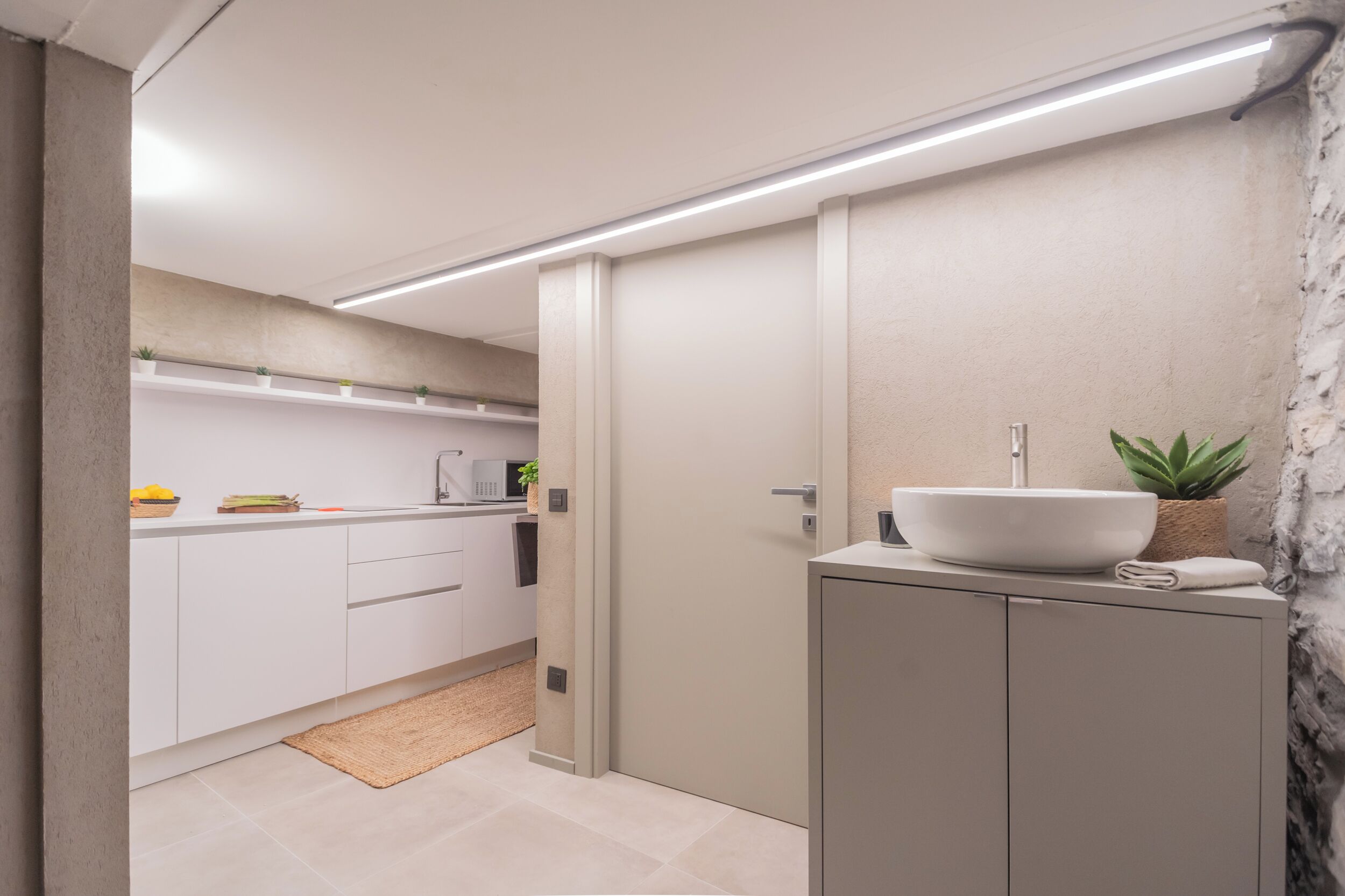 A modern bathroom with a white sink, a towel, and a potted plant.