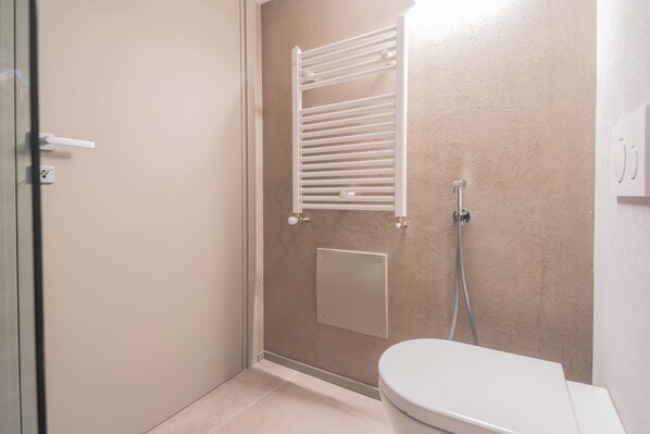 A bathroom with a shower, toilet, and a towel rack. - Urio's Castle Suites by Rent all Como (Carate Urio)