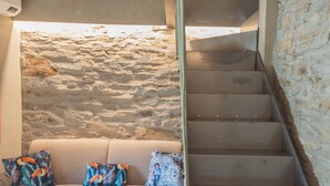 A staircase with a stone wall backdrop, a beige sofa with patterned cushions, and candles on the steps. - Urio's Castle Suites by Rent all Como (Carate Urio)