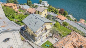 A residential area with a prominent yellow building featuring a balcony and a small garden. - La Quiete With Private Garden by Rent all Como (Laglio)