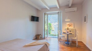 Un dormitorio con cama, televisión, zona de comedor con mesa y sillas, y vistas al exterior.