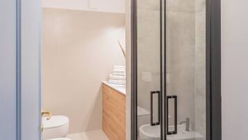 A modern bathroom with a toilet, sink, and shower area.