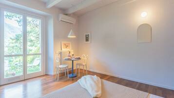 A bright room with a large window, a round table with chairs, and a white rug.
