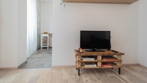 Una habitación con un mueble bajo de madera para televisión, un televisor de pantalla plana y un estante superior con una planta.