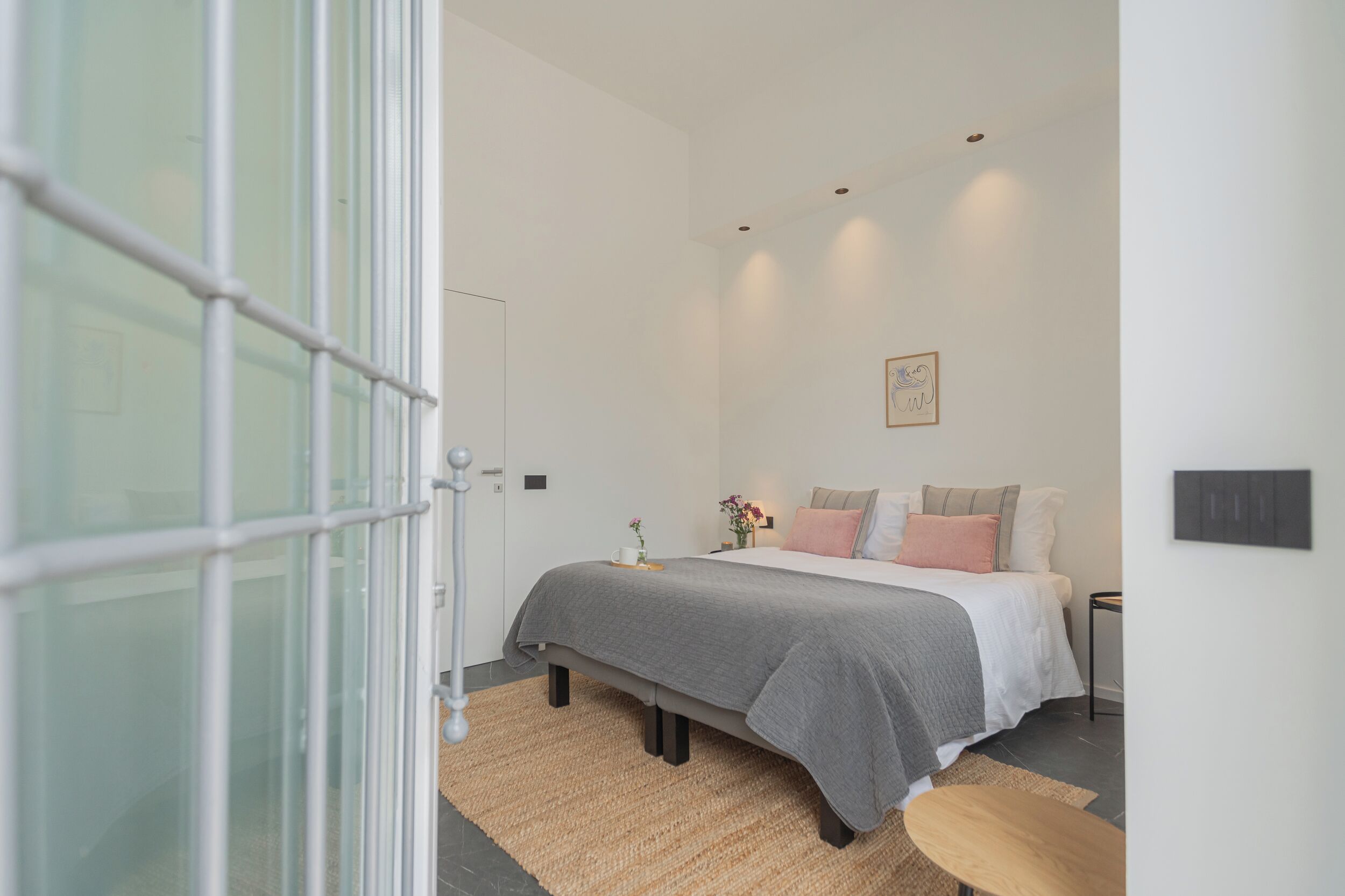 A modern bedroom with a bed, bedside table, and a small rug.