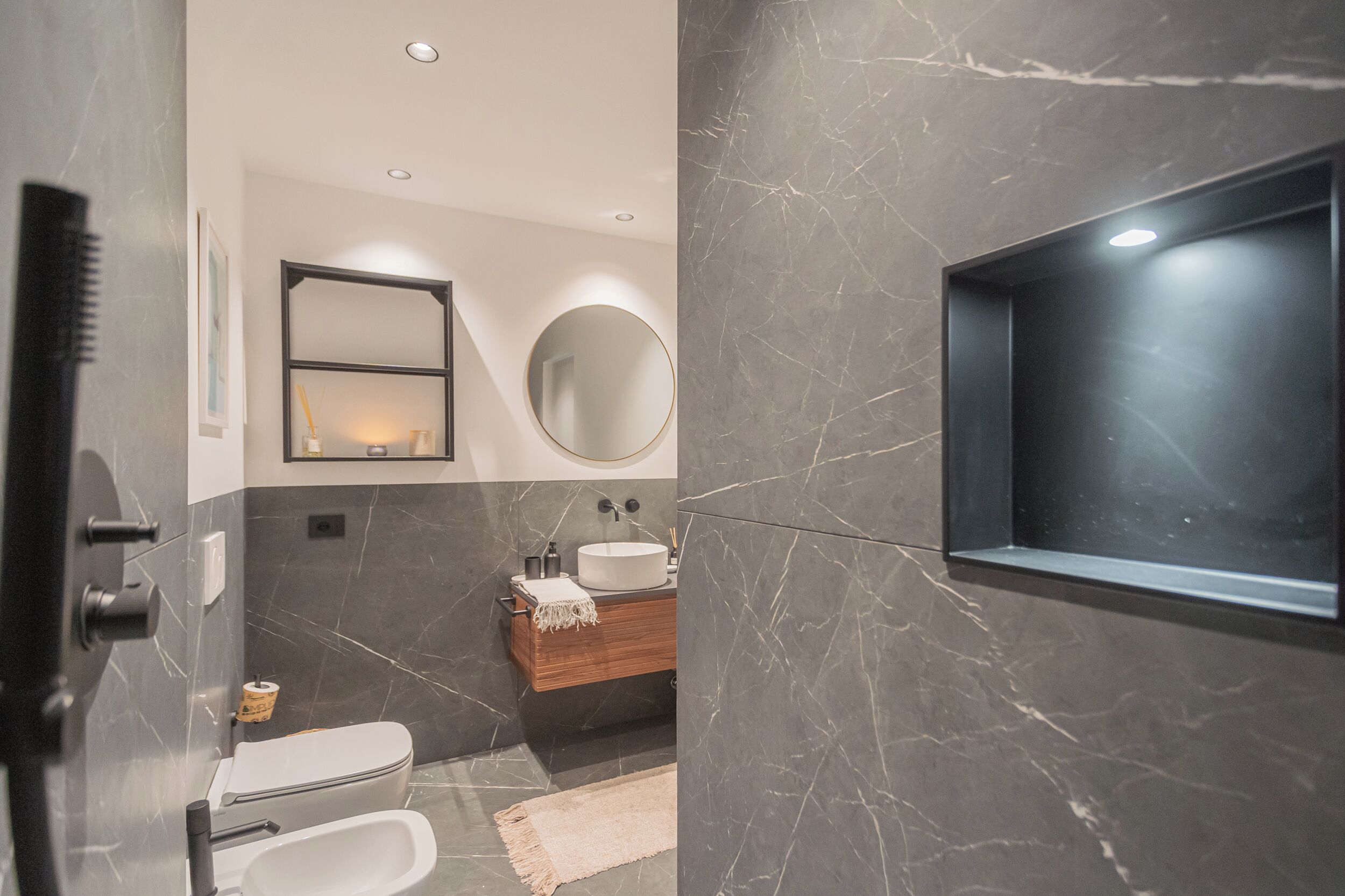 Un baño moderno con inodoro, bidé, tocador y espejo.