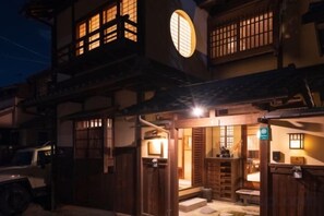 En traditionell japansk byggnad med en träfasad, en tydligt markerad entré och ett fordon parkerat utanför.