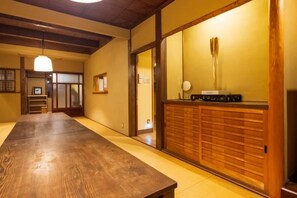 Ett traditionellt japanskt rum med tatamimattor på golvet, ett träbord, en skjutdörr och en receptionsdisk med en telefon.