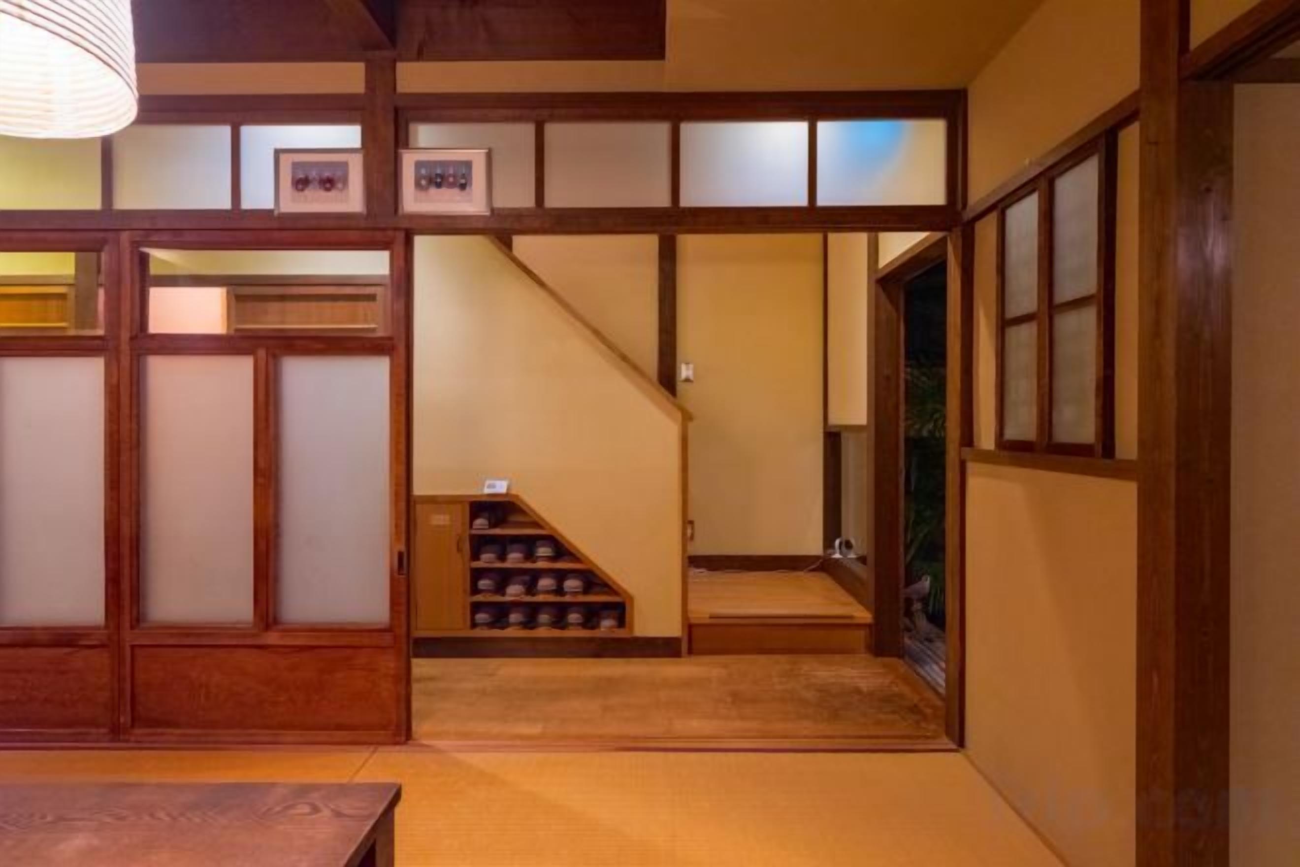 A traditional Japanese interior with tatami flooring, sliding doors, and a staircase leading to an upper level.