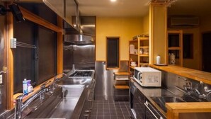 A modern kitchen with stainless steel appliances, wooden cabinets, and a black tiled floor. - Shimizu Kozuki 6min walk to Kiyomizu-dera Temple (Kyoto)