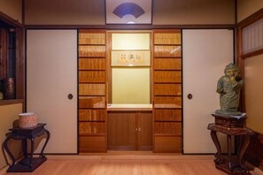 A traditional Japanese room with sliding doors, a small table with a decorative item, and a statue on a stand. - Shimizu Kozuki 6min walk to Kiyomizu-dera Temple (Kyoto)