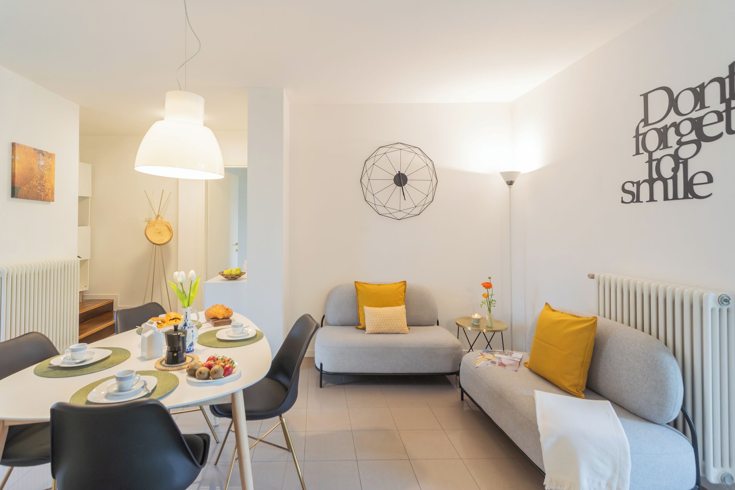 Un salon moderne avec une table à manger, un canapé et une horloge murale.