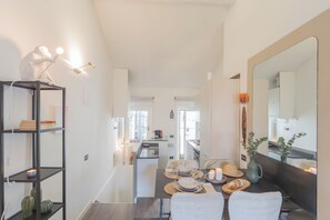 Enjoy meals in a spacious dining area with a large mirror adding depth and a kitchen nearby.