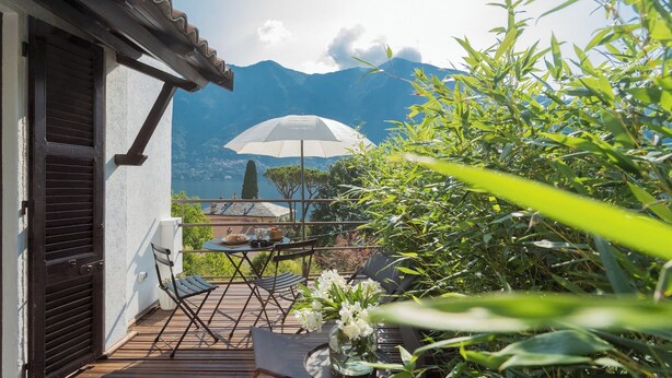 Ein Balkon mit Tisch, Stühlen und einem weißen Sonnenschirm.