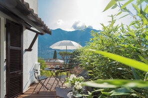 Uma varanda com mesa, cadeiras e um guarda-sol branco.