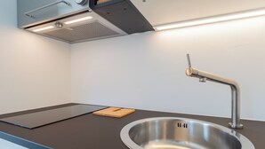 Eine moderne Küche mit einem Edelstahlspülbecken, einem Holzschnittbrett und einer eleganten schwarzen Arbeitsplatte.