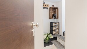 Eine Holztür mit Metallbeschlag, ein Wandhaken mit Haken, ein Holzregal mit einer Weltkugel und ein schwarzer Stauraum mit Schubladen.