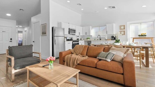 A modern living room with a sofa, a coffee table, and a dining area with a table and chairs.