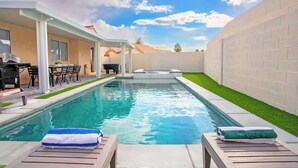 A swimming pool with lounge chairs and a barbecue area.