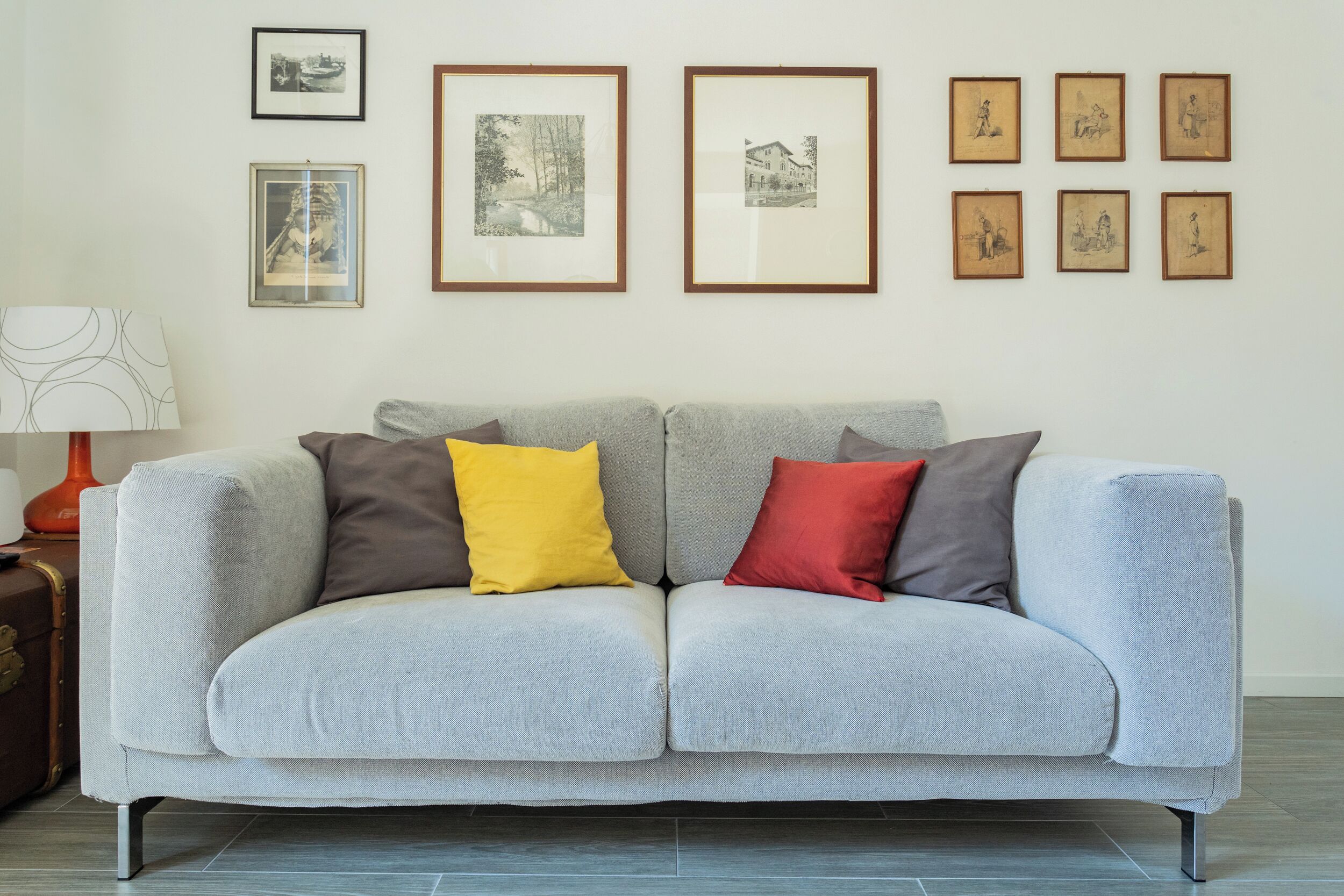 A light grey sofa with two cushions in grey, yellow, and red.