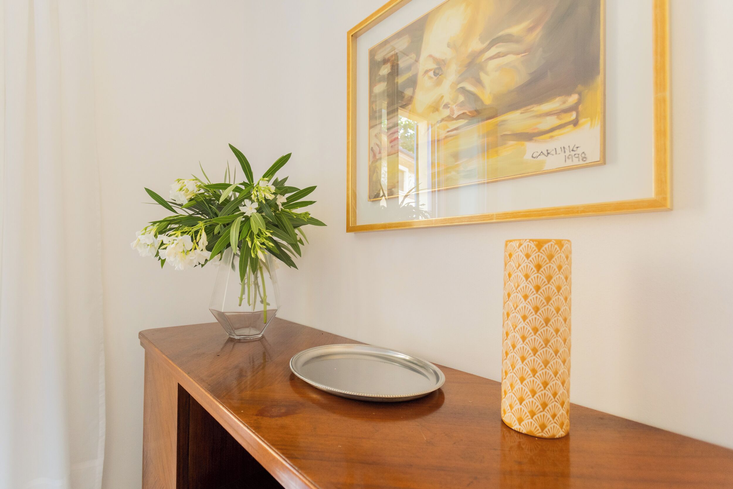 Une table en bois sur laquelle se trouvent un vase de fleurs, une assiette et un vase décoré.