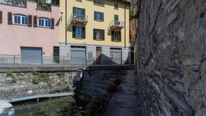 Un callejón estrecho con un muro de piedra a un lado y un edificio con balcones al otro.