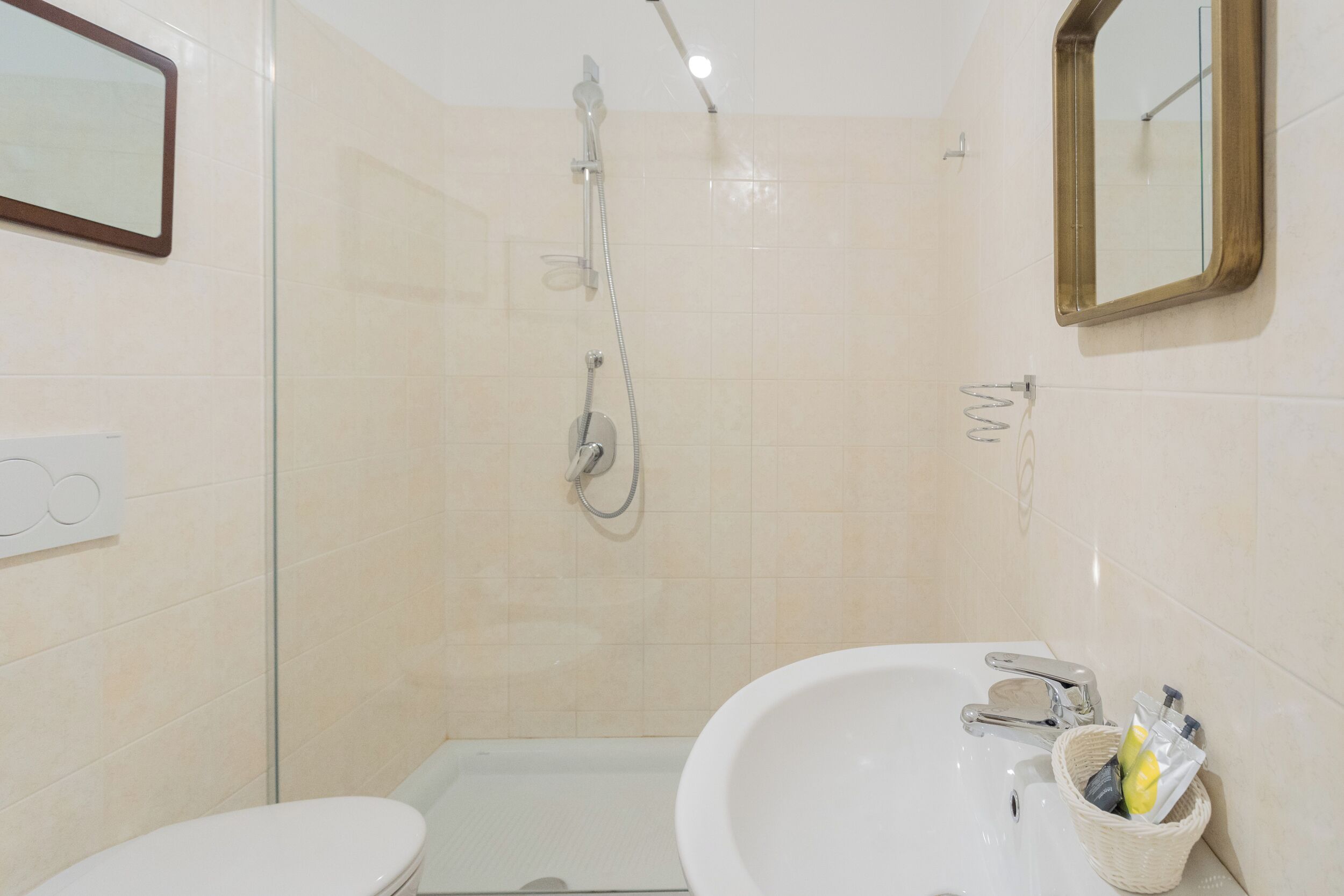A bathroom with a toilet, a sink, a shower, and a mirror.